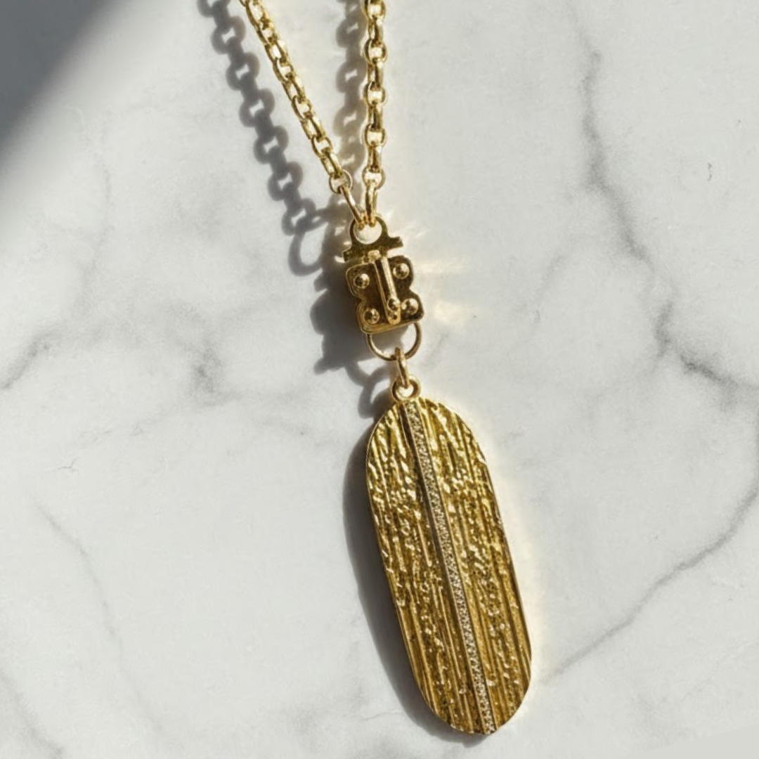 Handcrafted gold filled necklace holding a vertical gold feather pendant.