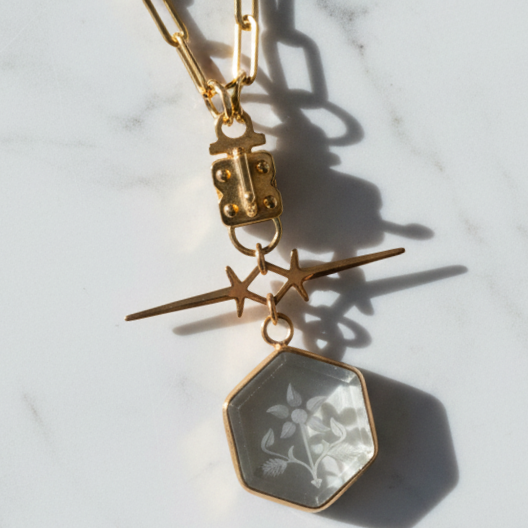 Sennod gold paperclip link necklace styled with a custom hexagon vignette pendant charm on a marble background