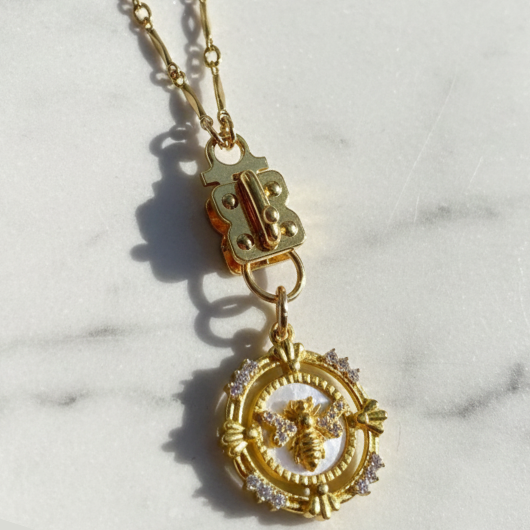 Sennod Jewelry "Isabelle" 14K gold-filled marquis bar and link vignette chain featuring a gold butterfly pendant on a marble background.